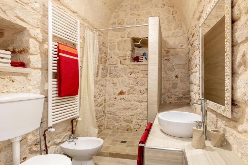 une salle de bain en pierre avec un lavabo et des toilettes dans l'établissement Villa Amico by Villa Plus, à Grottaglie
