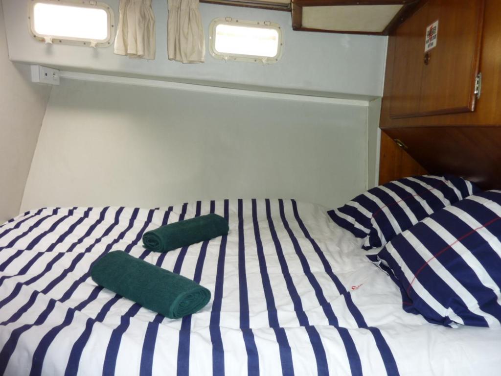 - un lit avec 2 serviettes vertes et 2 oreillers dans l'établissement Bateau PAPAYE, à Sète