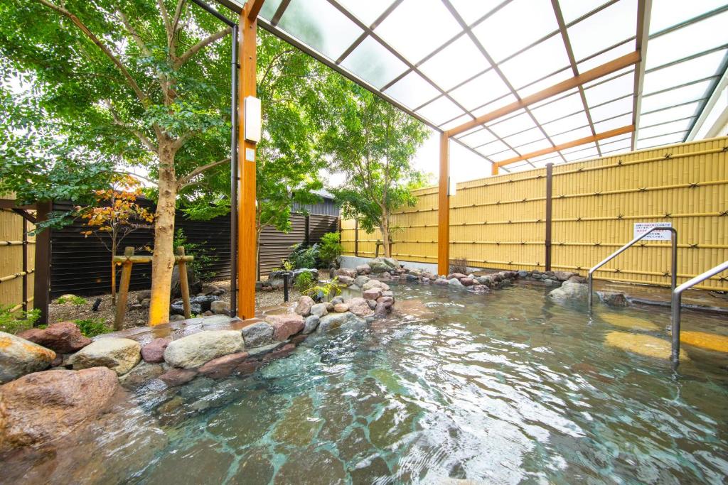 une piscine d'eau avec des rochers dans une cour arrière dans l'établissement Akarinoyado Togetsu, à Beppu