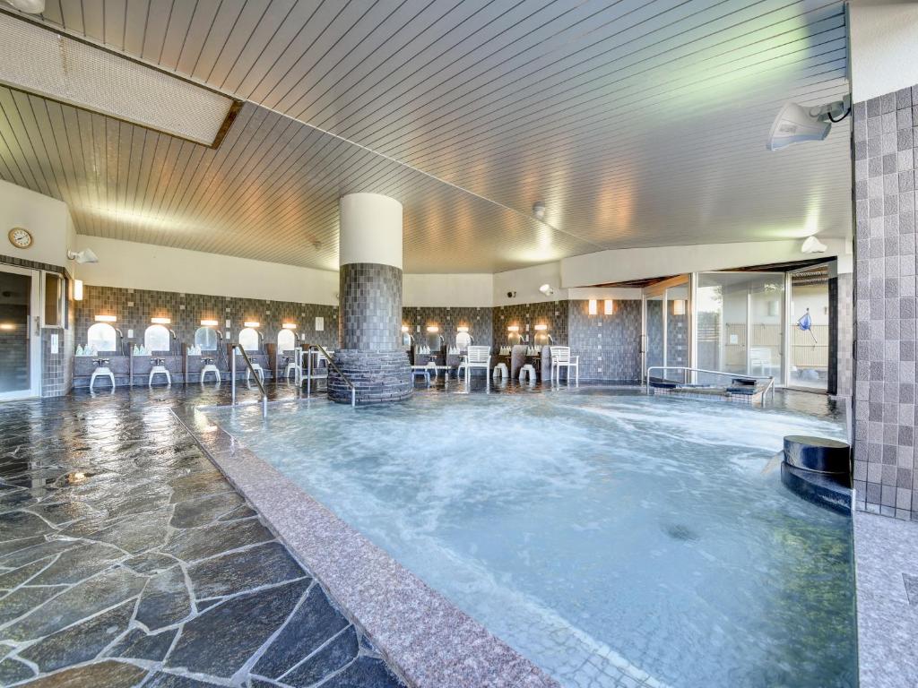 - une grande piscine dans le hall de l'hôtel avec des chaises dans l'établissement Yatsuo Yume no Mori Yuyu kan, à Toyama