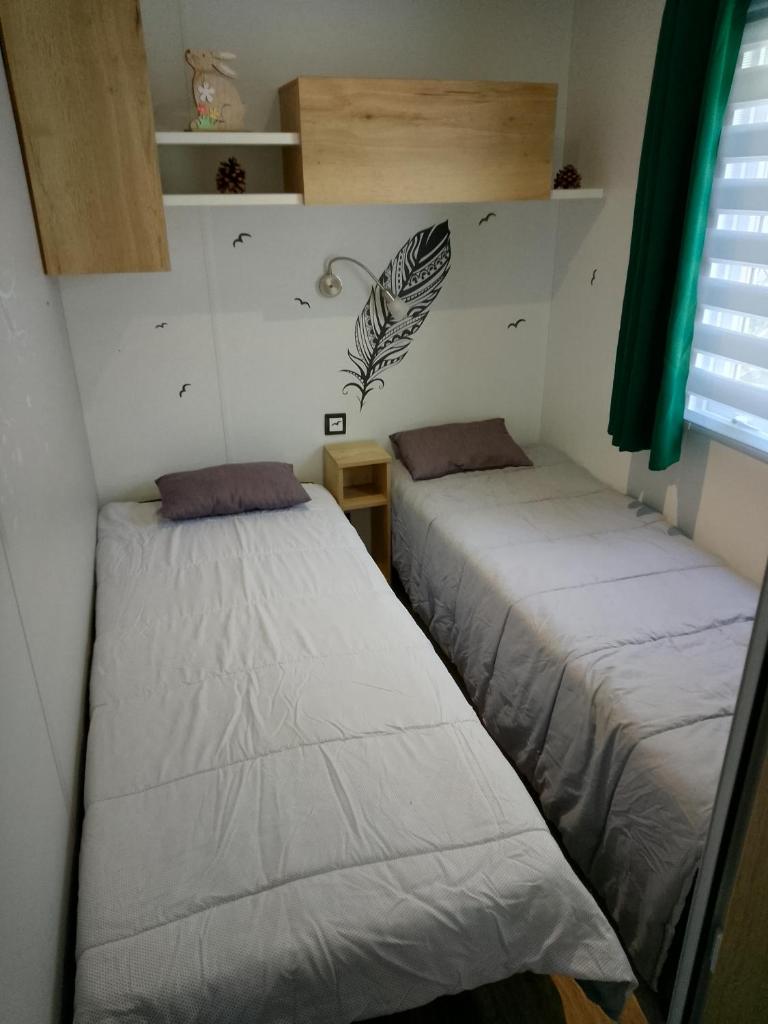deux lits dans une petite pièce avec une fenêtre dans l'établissement JOLI MOBILHOME 8 PERS climatisé CA62, à Vias 19 autres photos