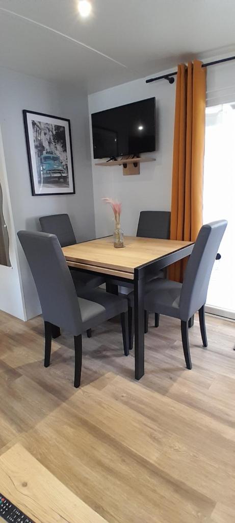 une table à manger avec des chaises et une télévision dans l'établissement JOLI MOBILHOME 8 PERS climatisé CA62, à Vias