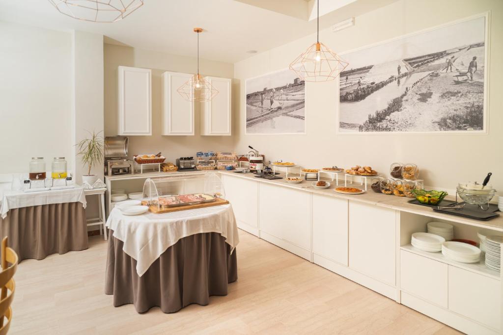 une cuisine avec des placards blancs et une table avec de la nourriture. dans l'établissement Hotel Ondina e Milazzo, à Cervia