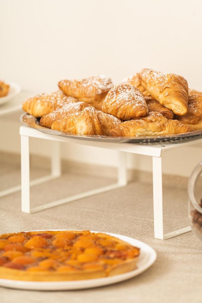 - un plateau de viennoiseries sur une table avec une assiette de pain dans l'établissement Hotel Ondina e Milazzo, à Cervia