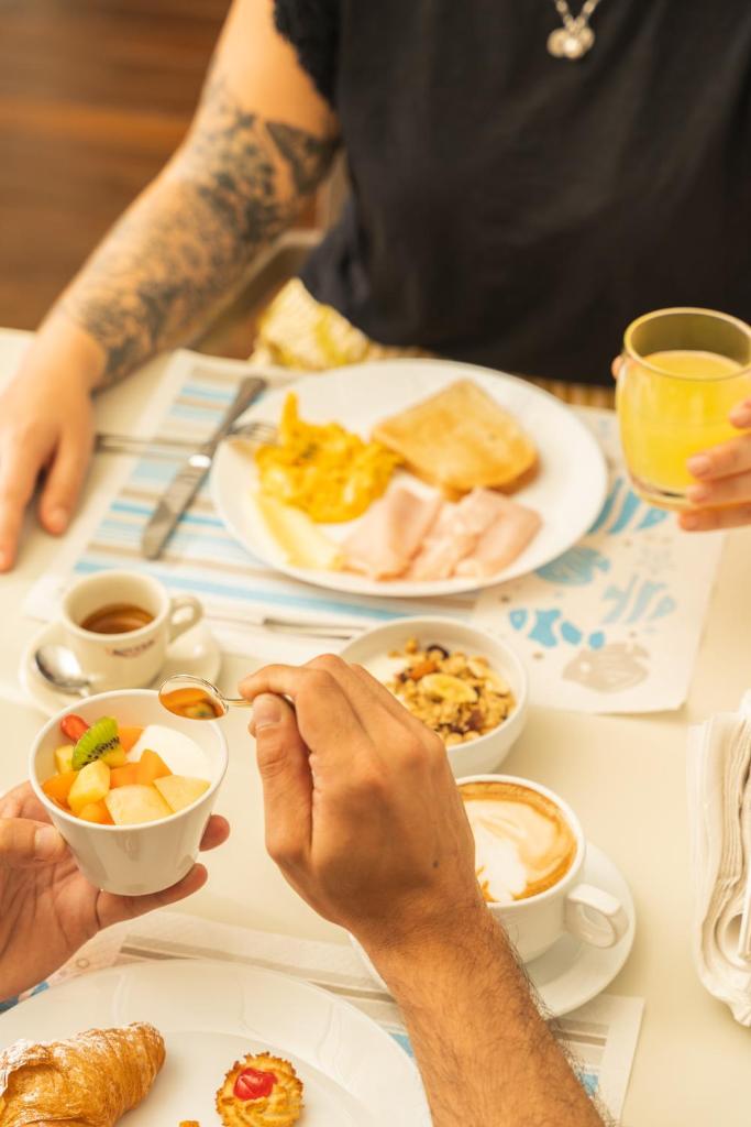 une personne assise à une table avec des aliments pour le petit-déjeuner dans l'établissement Hotel Ondina e Milazzo, à Cervia