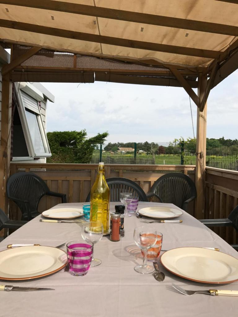 - une table avec des assiettes, des verres et une bouteille de vin dans l'établissement Mobil home IRM Excellence dans parc Natura 2000 Lac des rêves piscine ect sous fun pass, à Lattes