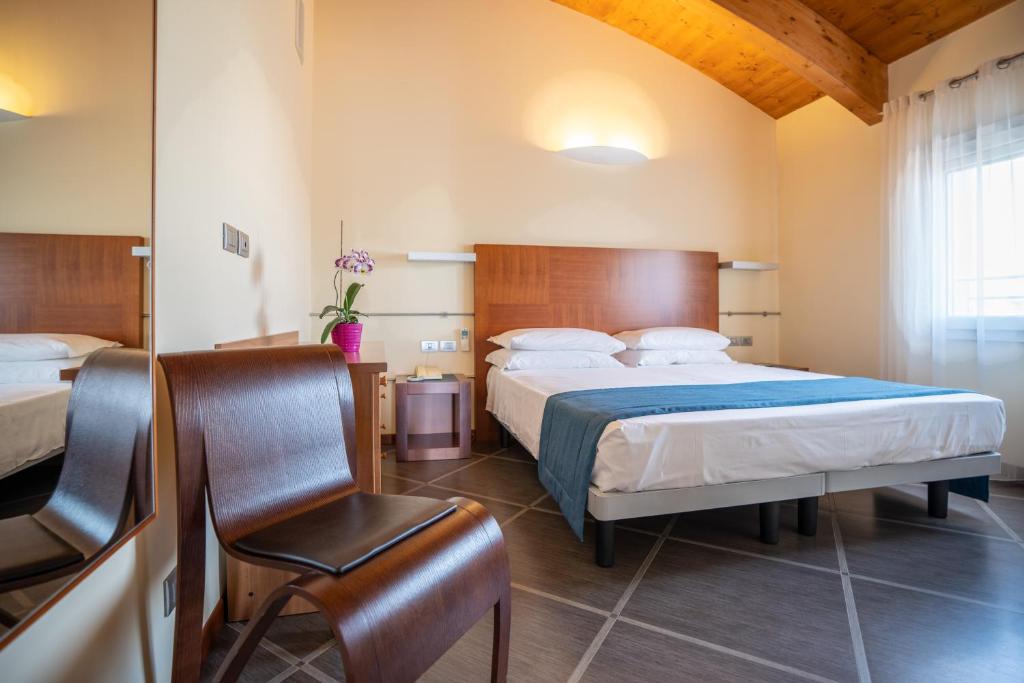 une chambre avec un lit et une chaise dedans dans l'établissement Hotel Coppe Jesolo, à Lido di Jesolo