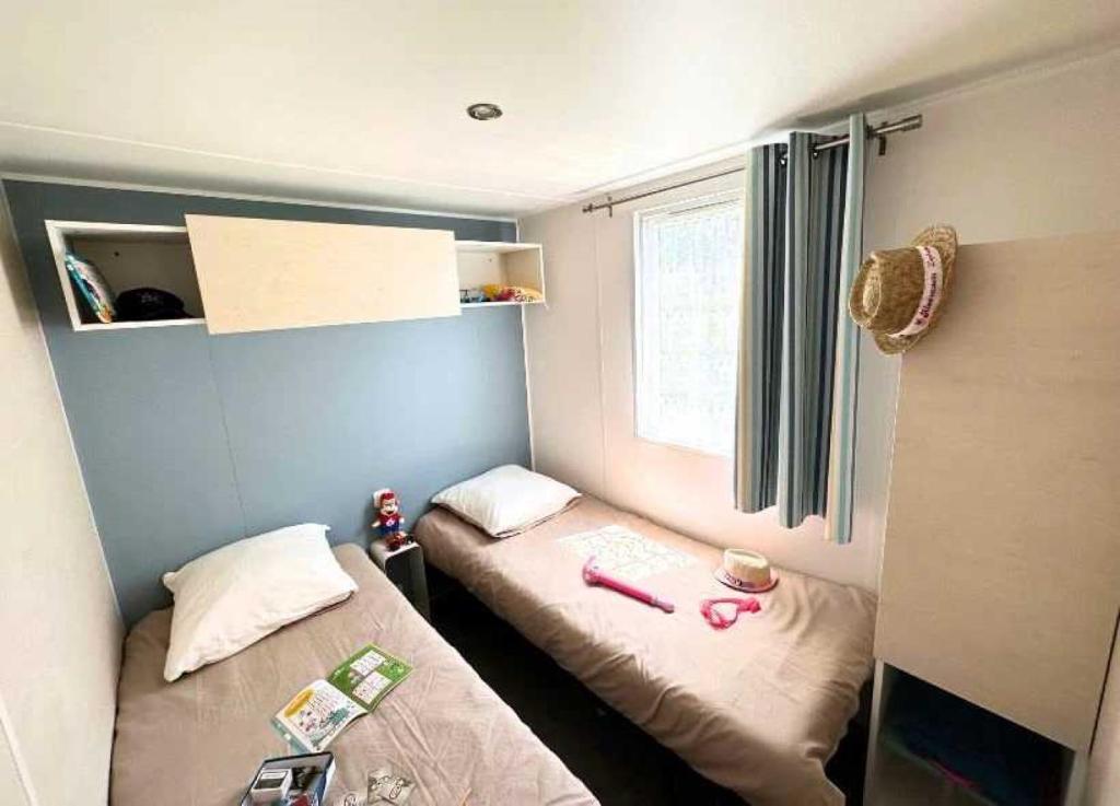une petite chambre avec deux lits et une fenêtre dans l'établissement Camping 5 étoiles - Parc aquatique - eei0fd, à Saint-Jean-dʼOrbetiers