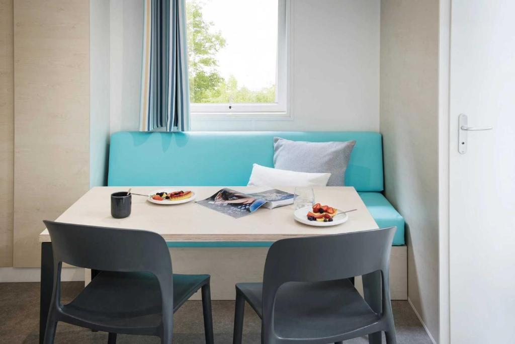 une table et des chaises avec des assiettes de nourriture dessus dans l'établissement Camping 4 étoiles - Parc aquatique - eeiagh, à Sérignan