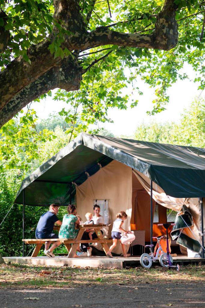 un groupe de personnes assises à une table dans une tente dans l'établissement Camping de Thoissey, à Thoissey