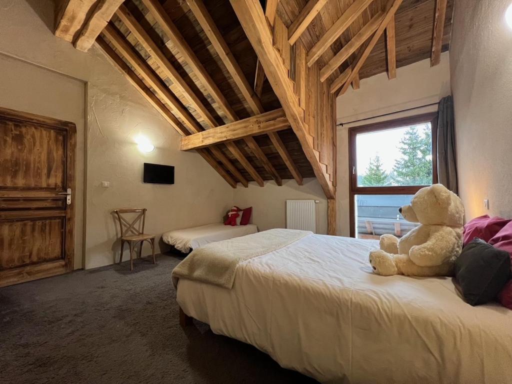 - un ours en peluche assis sur un lit dans une chambre dans l'établissement Nordique Symbiose, à Chapelle-des-Bois