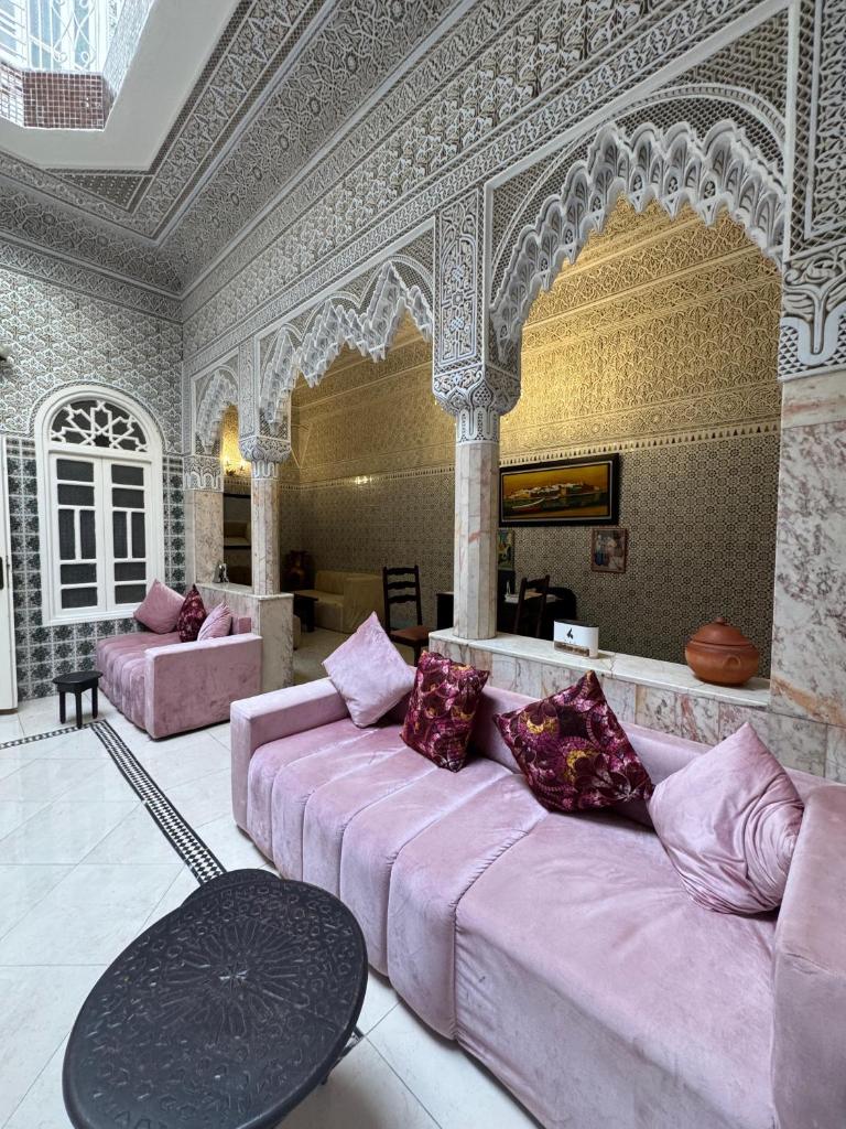 un salon avec un canapé rose et une table dans l'établissement Riad Blue Garden, à Rabat