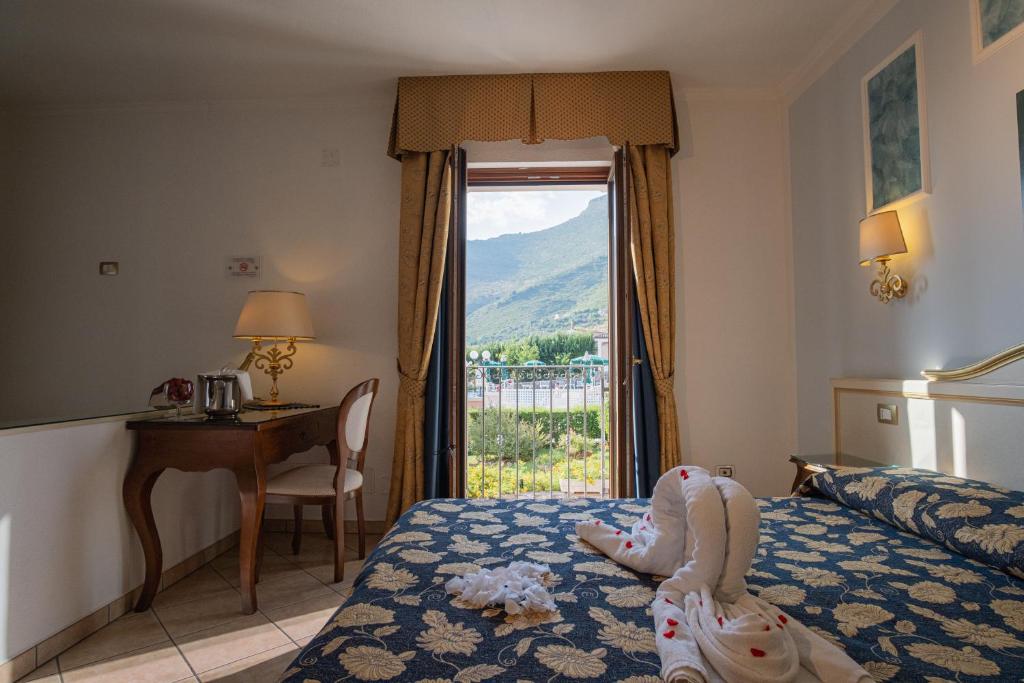 une chambre avec un lit avec un bureau et une fenêtre dans l'établissement Hotel Ristorante Borgo La Tana, à Maratea