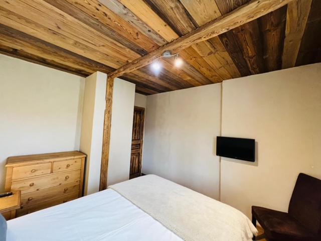 - une chambre avec un lit blanc et une télévision dans l'établissement Nordique Symbiose, à Chapelle-des-Bois