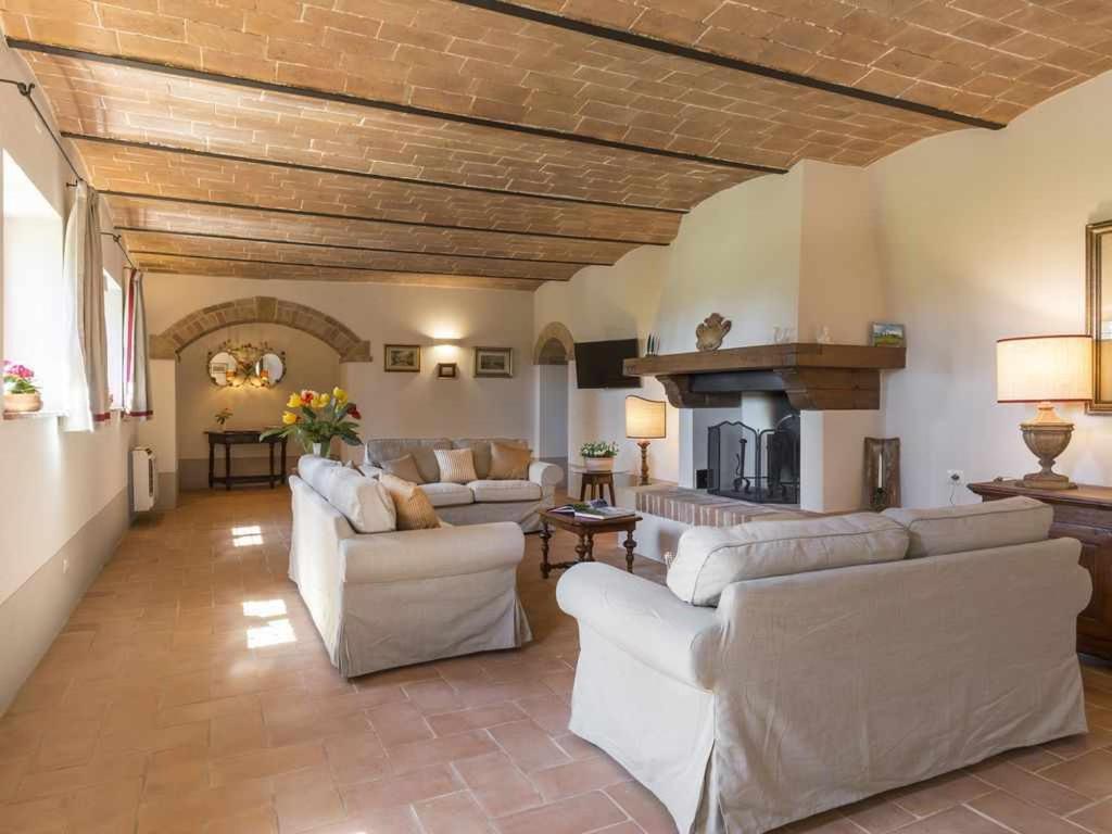 - un salon avec des canapés blancs et une cheminée dans l'établissement Villa I Cipressini piscina riscaldata spa Toscana, à Pienza