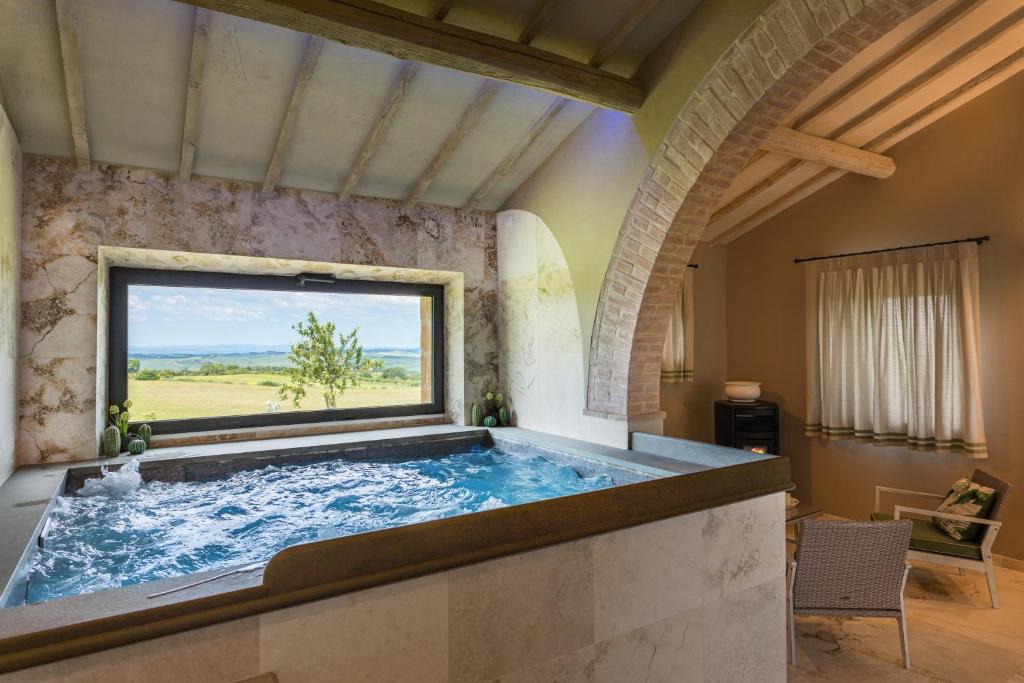 une baignoire jacuzzi dans une chambre avec fenêtre dans l'établissement Villa I Cipressini piscina riscaldata spa Toscana, à Pienza
