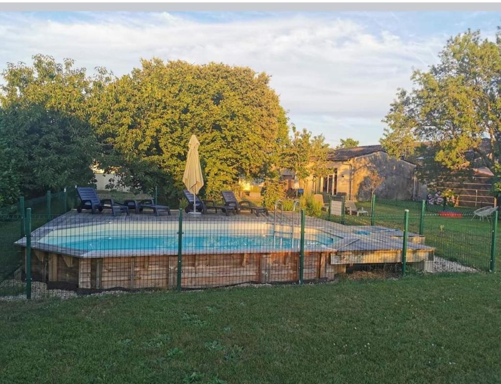 une piscine avec deux chaises et un parasol dans l'établissement La Vigneraie de Laura: Gîte Entre Vignes et Chênes, à Sainte-Colombe