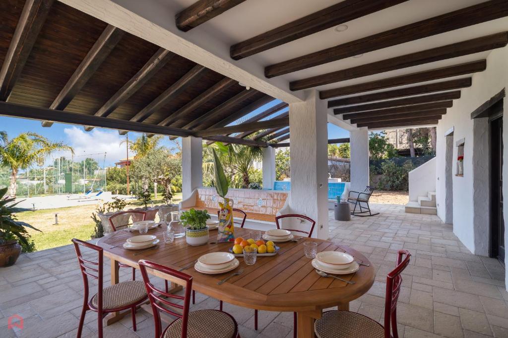 une table et des chaises en bois sur une terrasse dans l'établissement Villa a 300 Mt. dal Mare (Magaggiari) con campo da tennis, à Cinisi