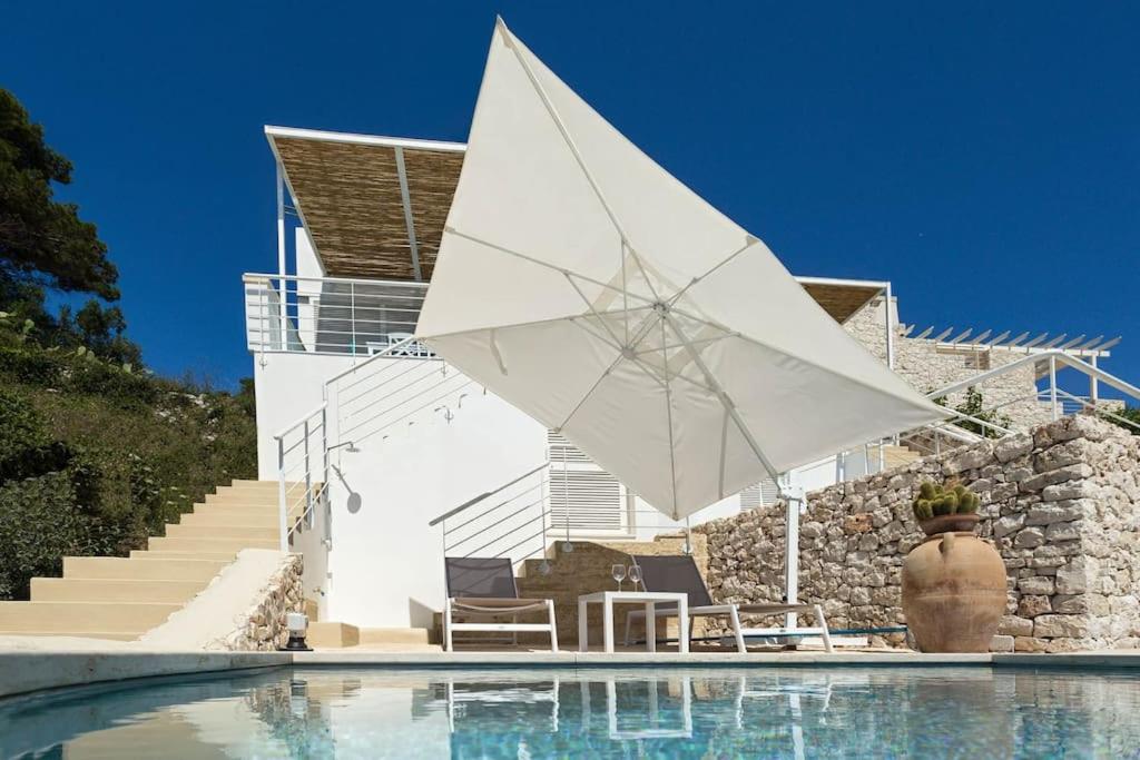 - un parasol blanc à côté de la piscine dans l'établissement Marinaia - Casa Aurora, à Diso