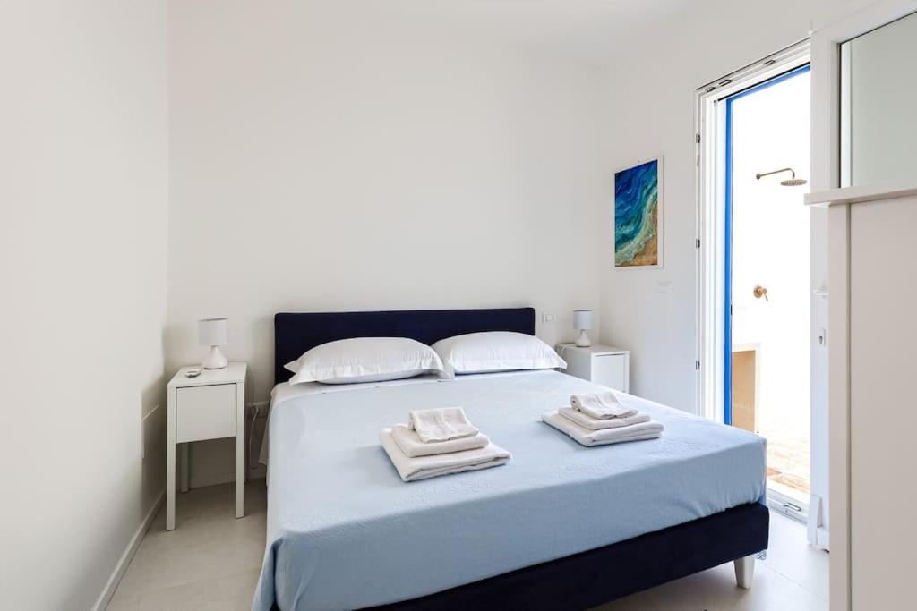 - une chambre blanche avec un lit bleu et des serviettes dans l'établissement Marinaia - Casa Aurora, à Diso