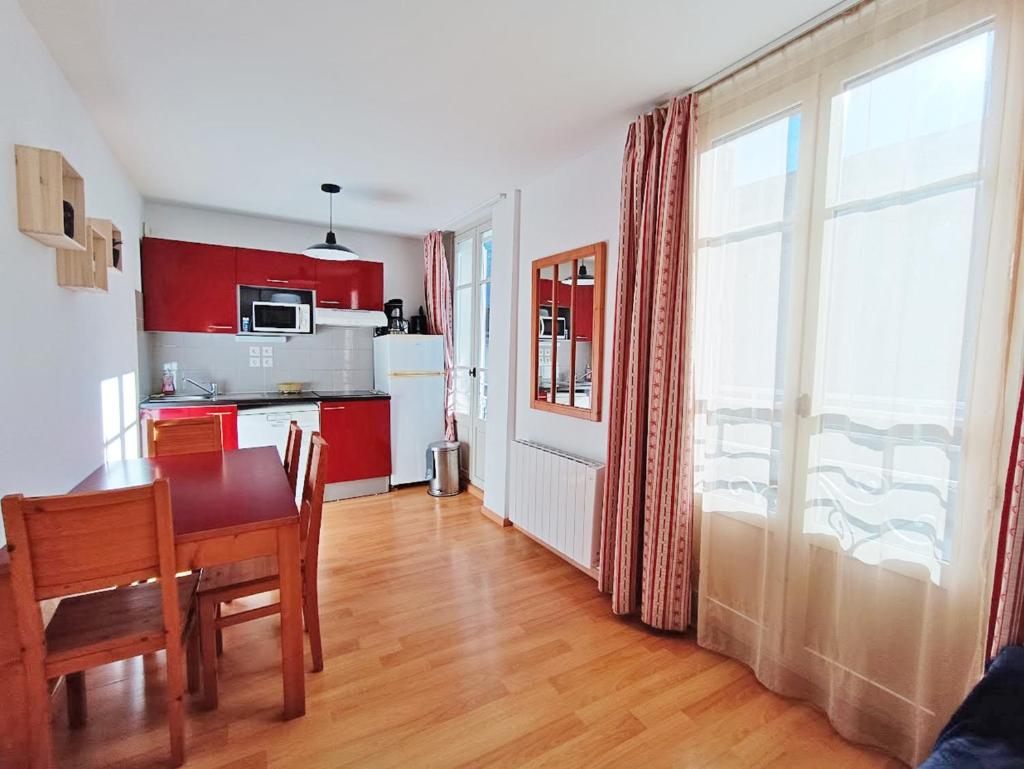 une chambre avec une table et une cuisine avec des placards rouges dans l'établissement Le Coudon, T2, centre Luchon, wifi, casier à skis, ascenseur, 5 personnes, à Luchon