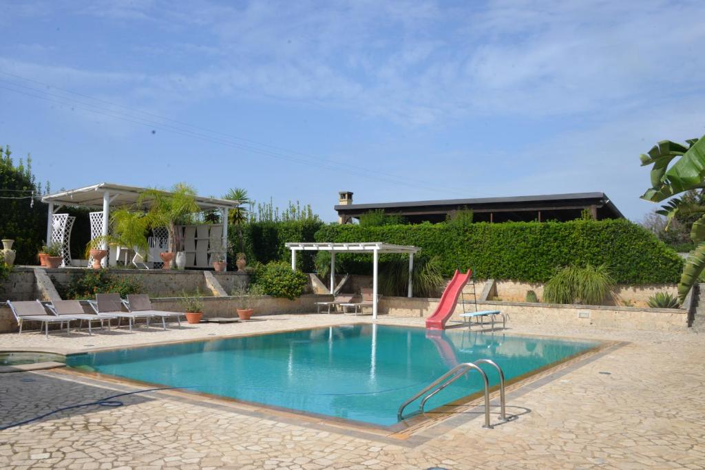 une piscine avec une chaise rouge et une maison dans l'établissement Marlù Luxury Rooms Pool and Garden, à Aradeo
