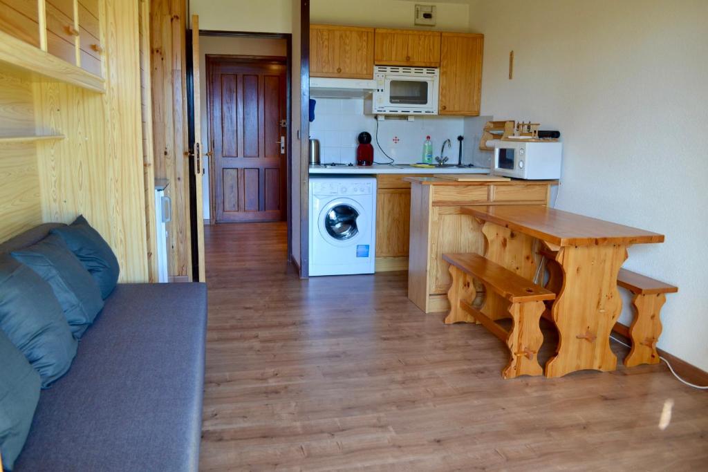 une cuisine avec une table et une cuisine avec une cuisinière dans l'établissement Studio cabine chaleureux à Pyrénées 2000 - WiFi et parking privé, à Bolquère-Pyrénées 2000