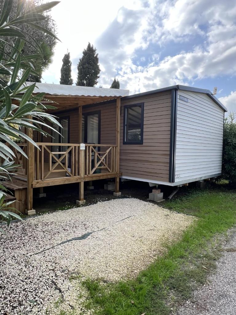 une petite maison avec un porche et une terrasse dans l'établissement Camping Del Mar B70, Mobile Home Excellence, 3 chambres, 6 personnes, 2 Salles de Bain, bord de mer, à Argelès-sur-Mer