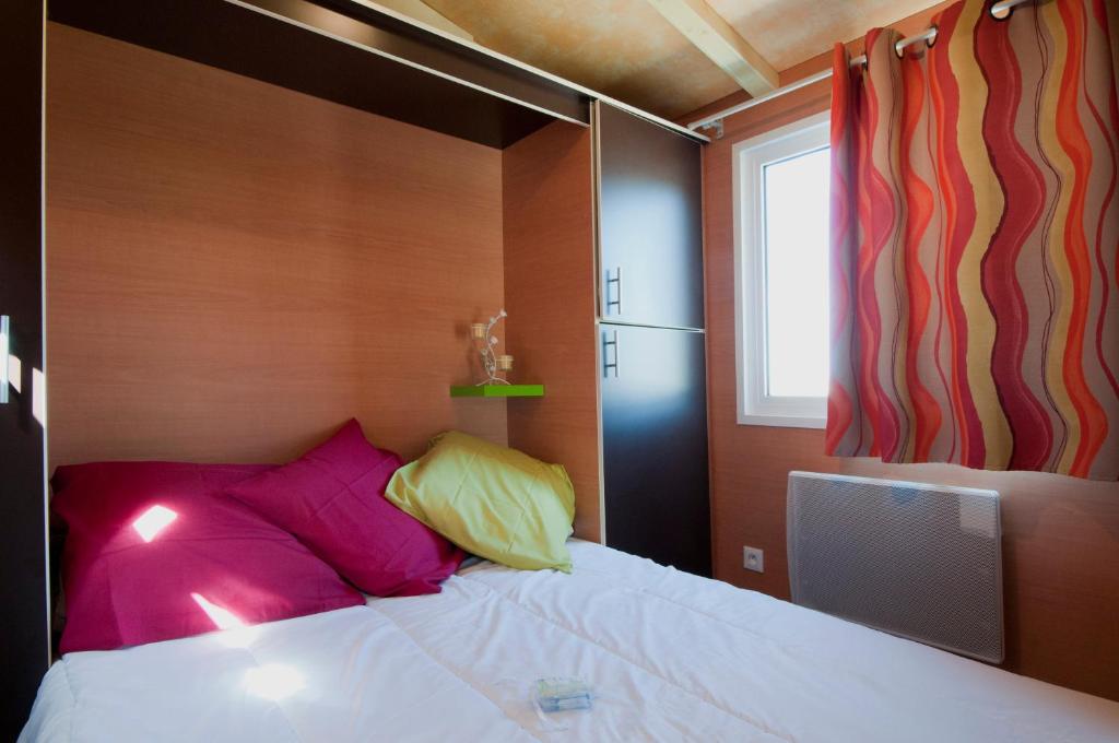 - une chambre avec un lit doté d'oreillers violets et jaunes dans l'établissement Nuits Insolites d Argonne, à Varimont