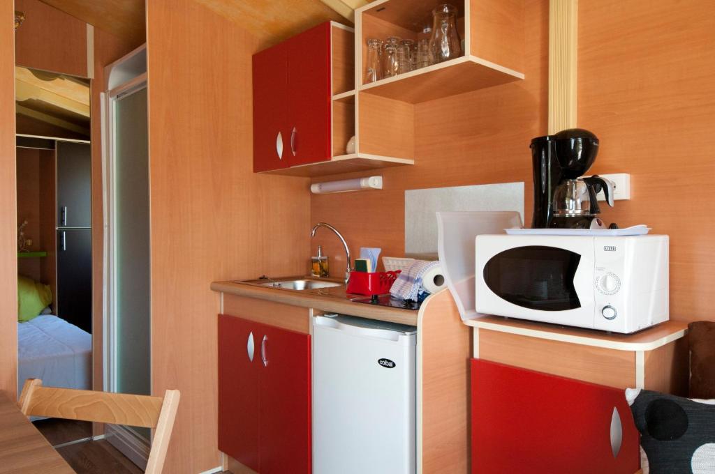 une petite cuisine avec un four micro-ondes blanc sur un comptoir dans l'établissement Nuits Insolites d Argonne, à Varimont