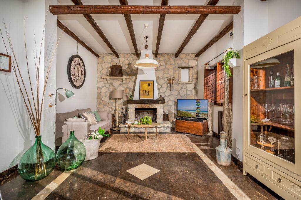 un salon avec une cheminée en pierre et une télévision dans l'établissement Il Giardino Dei Limoni 8, Emma Villas, à Ispica