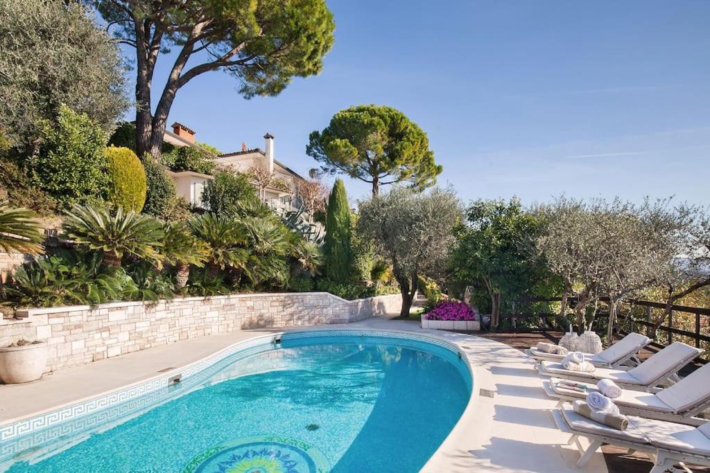 une piscine avec des chaises et des arbres et une maison dans l'établissement Villa Rosa del Garda Golf and Bike, à Garde