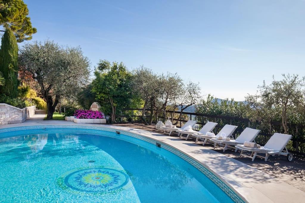 une piscine avec des chaises longues et une piscine dans l'établissement Villa Rosa del Garda Golf and Bike, à Garde
