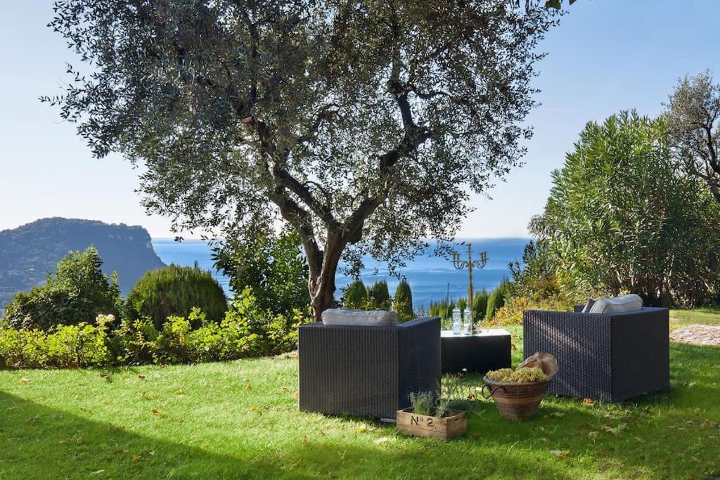 deux chaises assises dans l'herbe sous un arbre dans l'établissement Villa Rosa del Garda Golf and Bike, à Garde