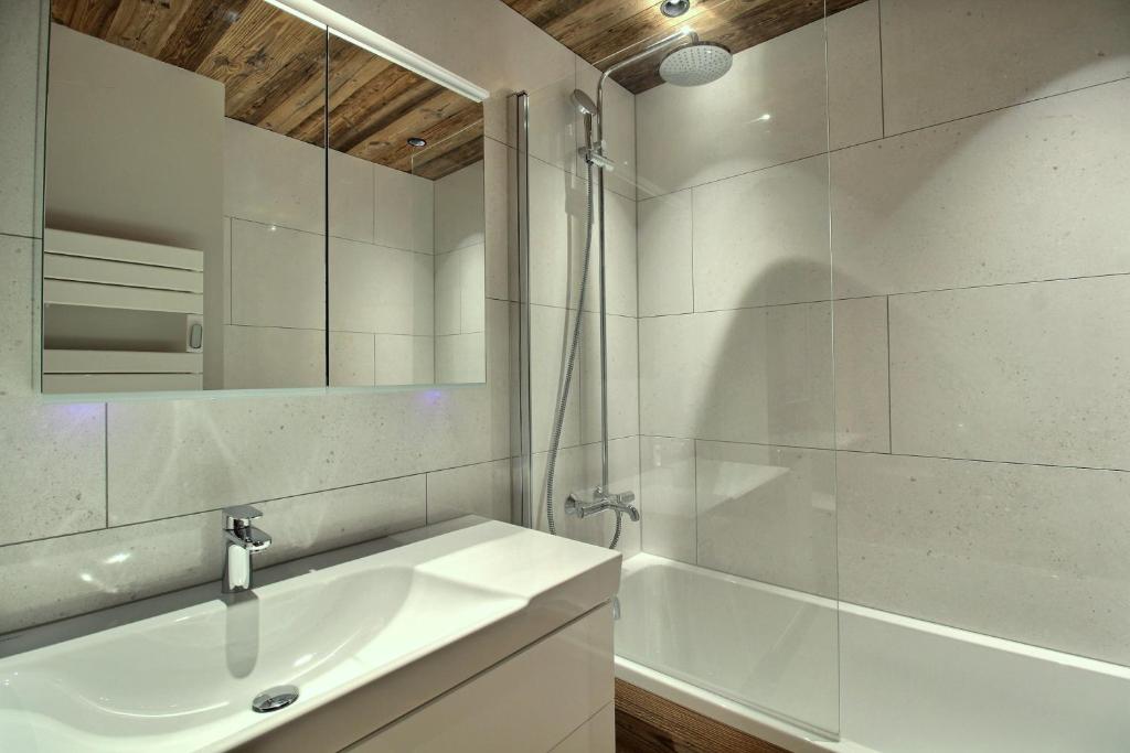une salle de bain avec un lavabo, une baignoire et un miroir dans l'établissement ARC 1950 - Appartement 8 personnes Duplex Cheminée - ski aux pieds - Sauna, Hammam, Jacuzzi, Piscine, à Arc 1950
