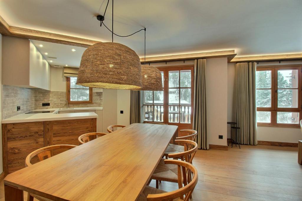 une cuisine et une salle à manger avec une table et des chaises en bois dans l'établissement ARC 1950 - Appartement 8 personnes Duplex Cheminée - ski aux pieds - Sauna, Hammam, Jacuzzi, Piscine, à Arc 1950