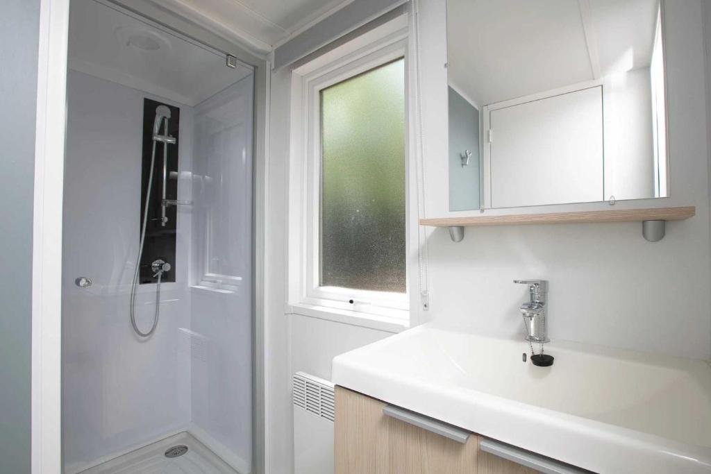 une salle de bain blanche avec un lavabo et une douche dans l'établissement Camping 4 étoiles - Piscine - ccafc0b, à Lamothe-Fénelon