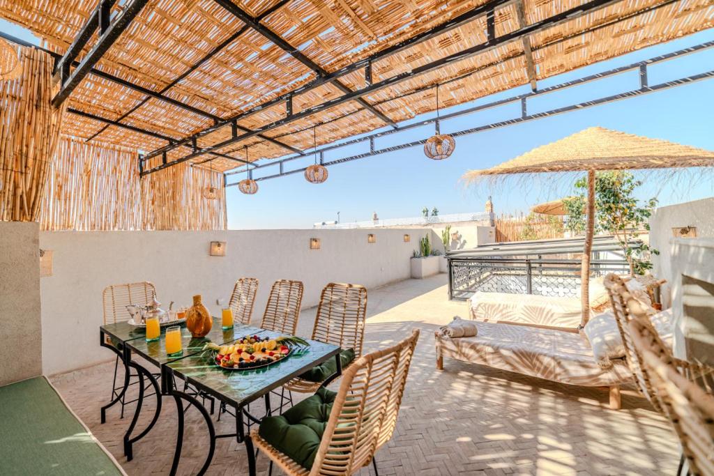 un patio avec une table, des chaises et un parasol dans l'établissement Riad Zemzem Au Coeur de la medina Petit dejeuner, à Marrakech
