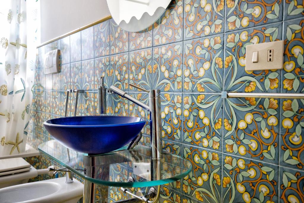 - une salle de bains avec un bol bleu sur un lavabo en verre dans l'établissement Sealight Villa Lipari - Vista e Piscina, à Lipari