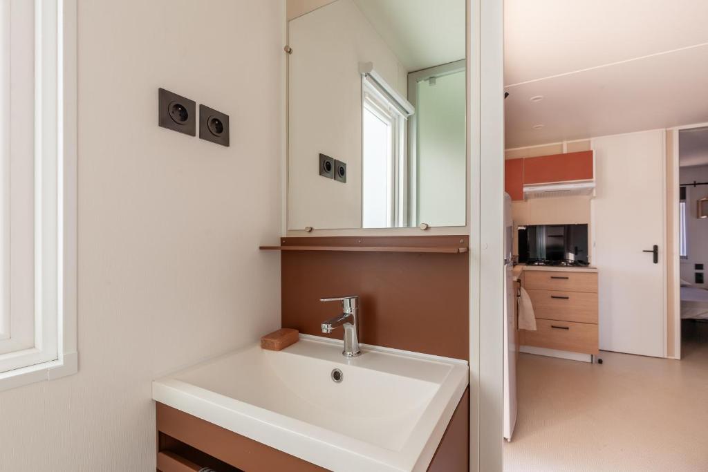 une salle de bain avec un lavabo et un miroir dans l'établissement MOBIL HOME Neuf FRONT DE MER TOUT CONFORT 5 LITS 6 personnes CARRY LE ROUET, à Carry-le-Rouet