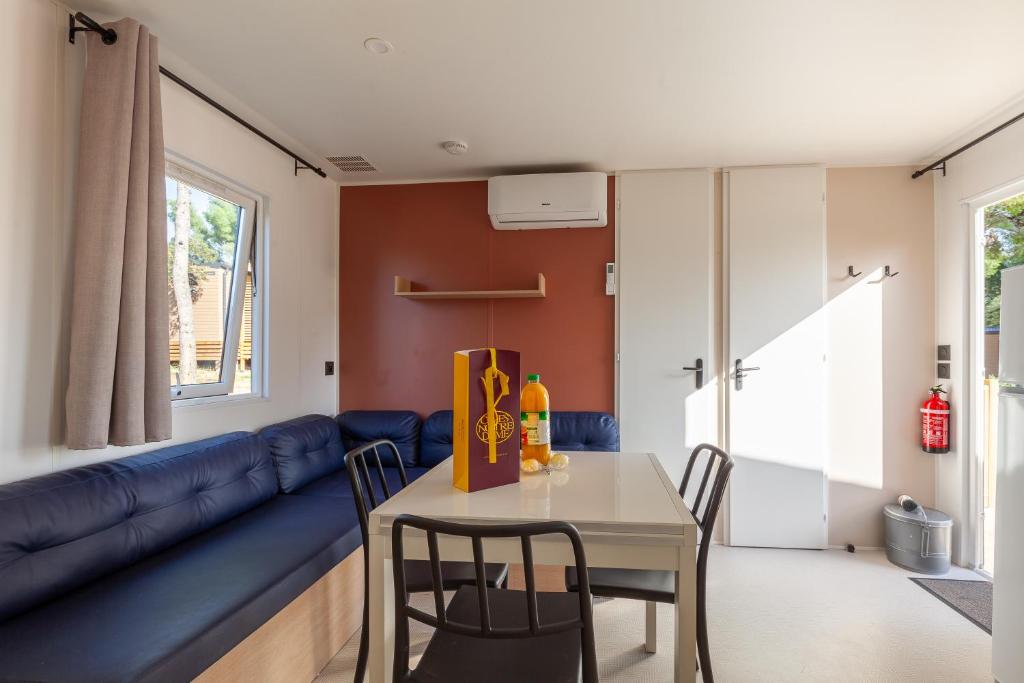 un salon avec un canapé bleu et une table dans l'établissement MOBIL HOME Neuf FRONT DE MER TOUT CONFORT 5 LITS 6 personnes CARRY LE ROUET, à Carry-le-Rouet