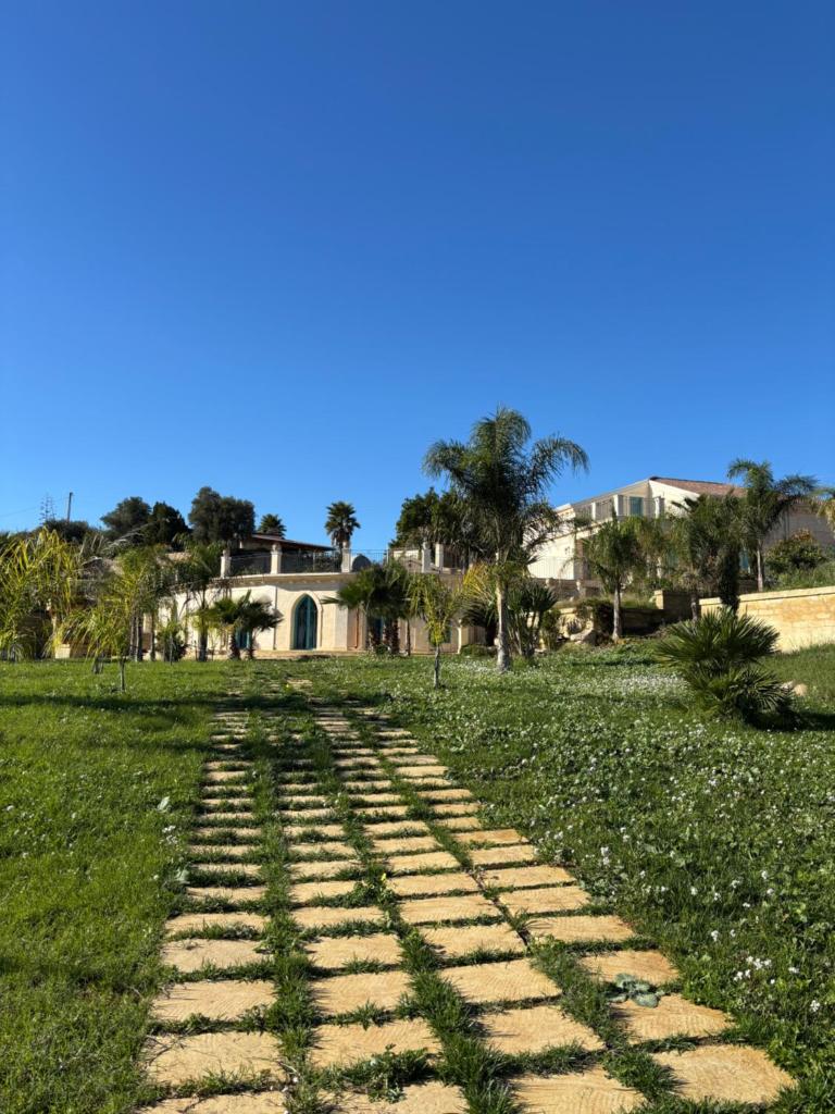 un chemin en briques dans un champ avec une maison en arrière-plan dans l'établissement Villa Brikinnia, à Lentini