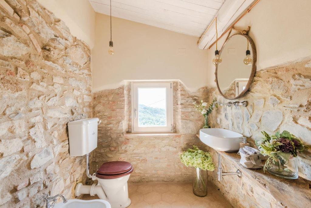 La salle de bains aux murs de pierre est pourvue de toilettes et d'un lavabo. dans l'établissement Le Due Terre Farmhouse, à Monsummano