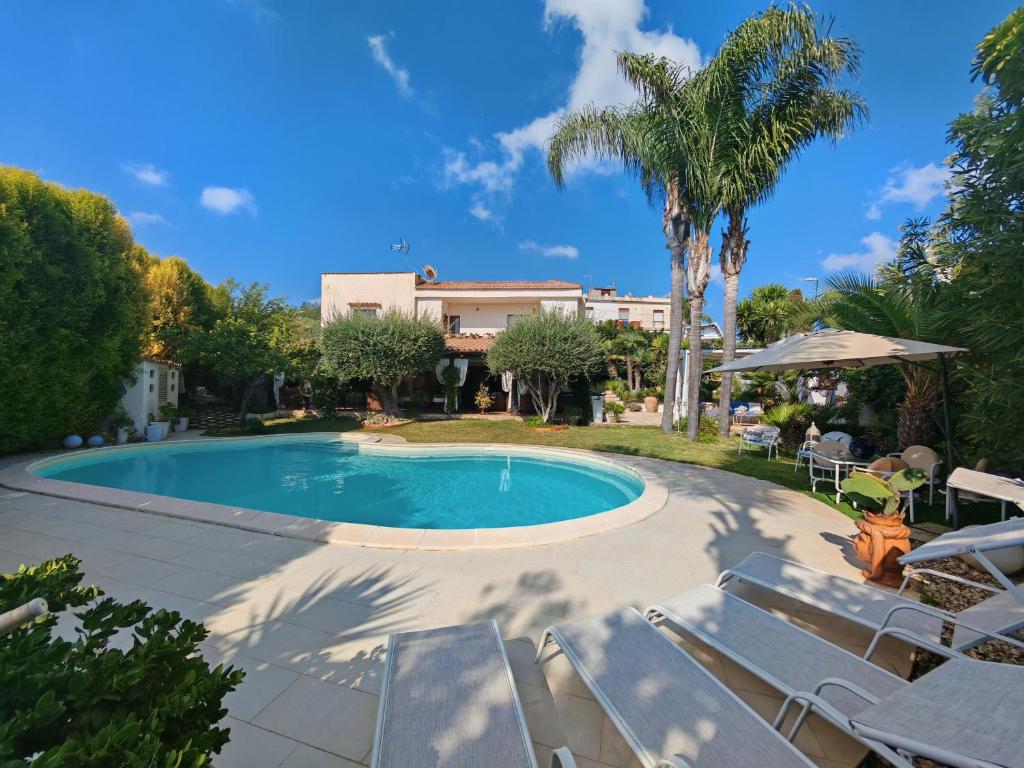 une piscine avec des chaises et une maison dans l'établissement The queen's house, à Agrigente