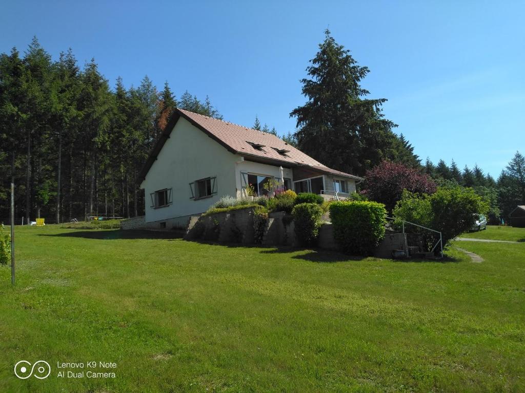 une maison dans une cour avec une pelouse verte dans l'établissement Gîte aux portes du Morvan, à Magnien