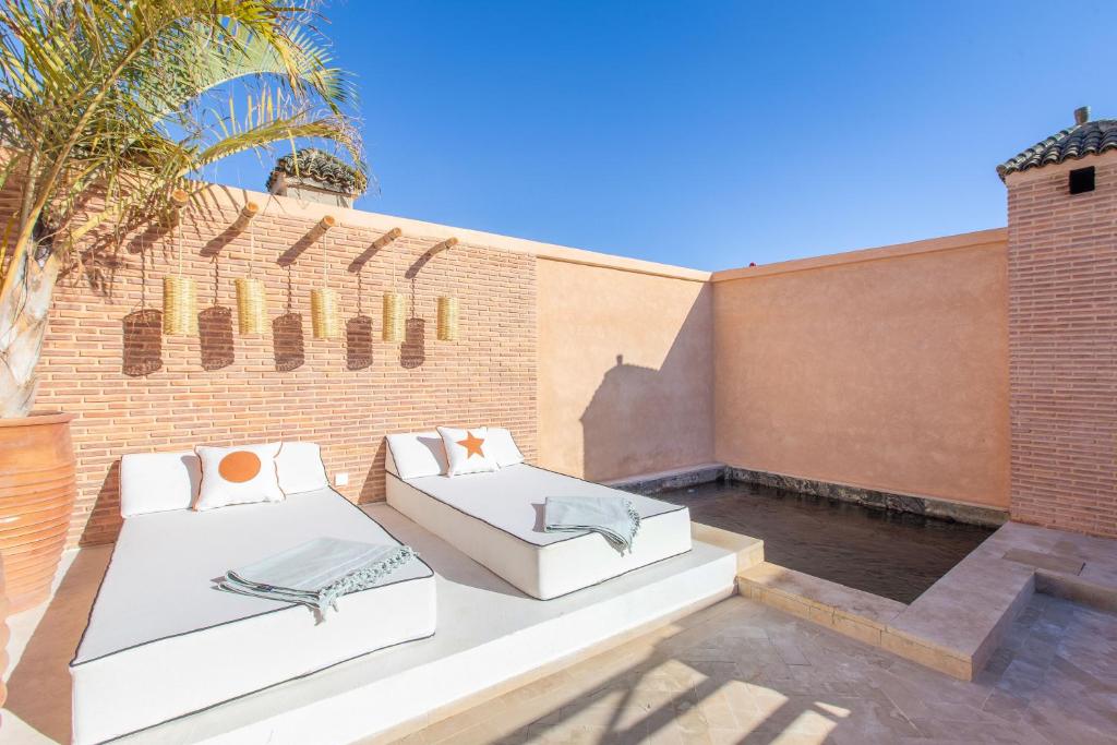 - 2 lits sur une terrasse avec un mur en briques dans l'établissement Dar KAJAM -Privatized Riad -10mn from Jamaa Al Fna, à Marrakech