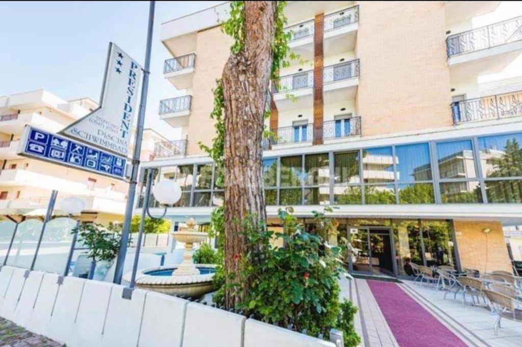 un bâtiment avec un arbre devant lui dans l'établissement Hotel President, à Cesenatico