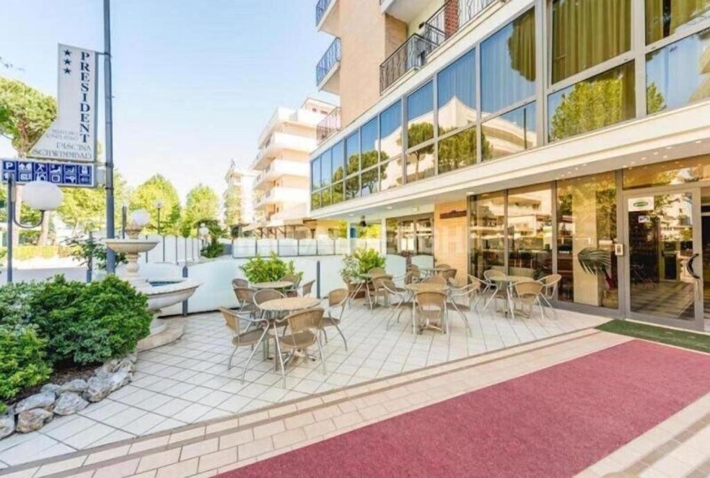 une terrasse avec des tables et des chaises devant un bâtiment dans l'établissement Hotel President, à Cesenatico