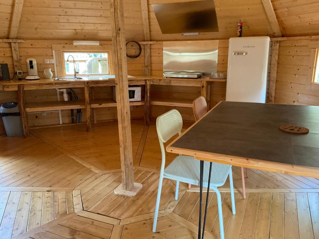 une cuisine avec une table et des chaises dans une cabine dans l'établissement Les cabanes de la palombière, à Allons