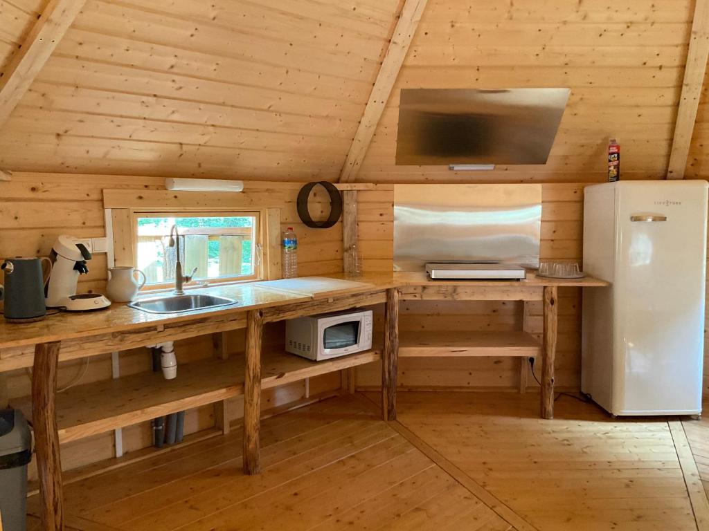 - une cuisine avec évier et réfrigérateur dans une cabine dans l'établissement Les cabanes de la palombière, à Allons